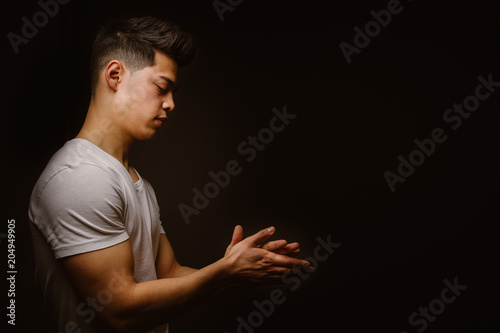 Side view of young man rubbing hand against black background photo