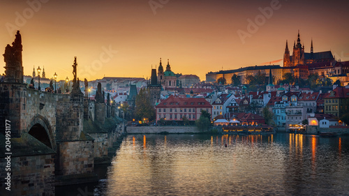 Panoramic view of night time illuminations of Prague Castle, Charles Bridge and St Vitus Cathedral reflected in the Vltava river. Pragua, Czech Republic.
