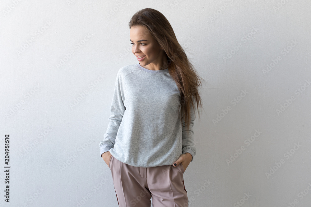 Beautiful woman in gray sweatshirt stands on white background. Mock-up. Beautiful woman in gray sweatshirt stands on white background. Mock-up.