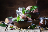 Chocolate ice cream with topping and fried pine nuts decorated with mint leaves, old wooden background, selective focus