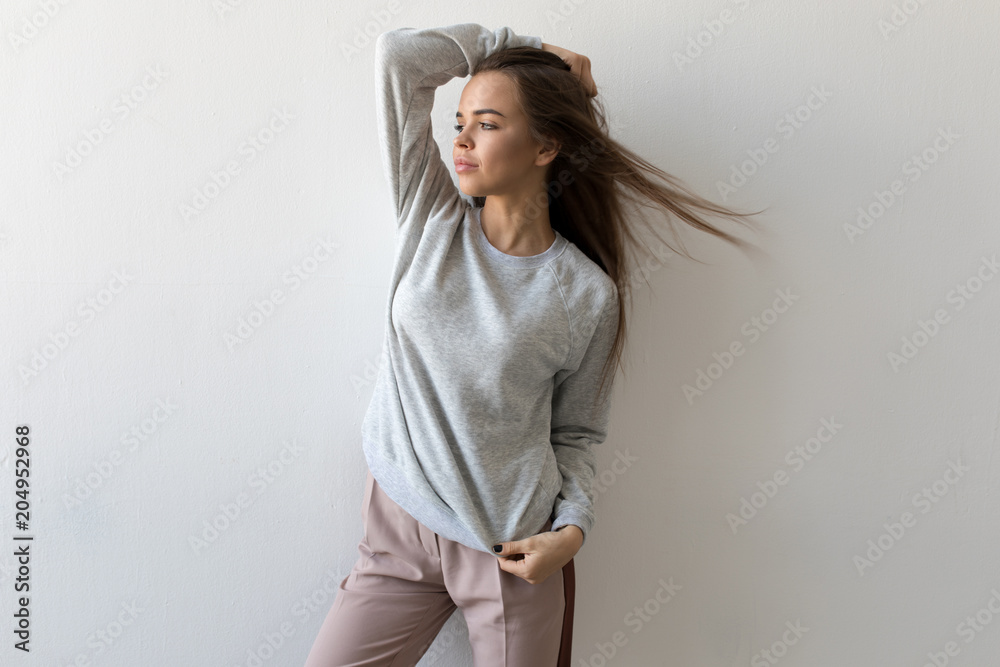 Beautiful woman in gray sweatshirt stands on white background. Mock-up. Beautiful woman in gray sweatshirt stands on white background. Mock-up.