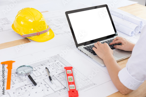  Woman Architect or engineer hands working on blueprint plans with a laptop and pencil a ruler, calculator, and engineering tools. Architect or engineer working on blueprint in office.