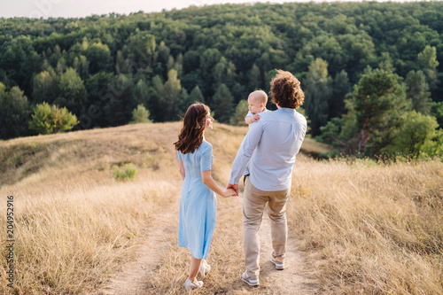 Young happy caucasian couple with little baby boy. Parents and son walking and having fun together. Mother and father playing with toddler outdoors. Family, parenthood, childhood, happiness concept.