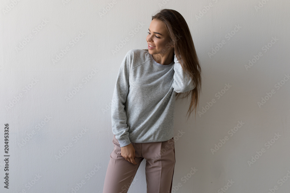 Beautiful woman in gray sweatshirt stands on white background. Mock-up. Beautiful woman in gray sweatshirt stands on white background. Mock-up.