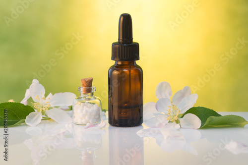 Bottle of homeopathic globules,homeopathic remedies and flowers