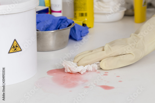 cleaning a spilled liquid next to a container for biological risk