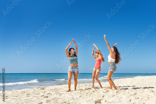 Young women dancing and smiling at the beach