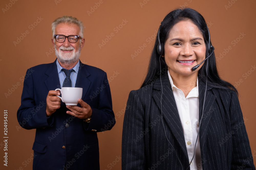 Mature multi-ethnic business couple against brown background Mature multi-ethnic business couple against brown background
