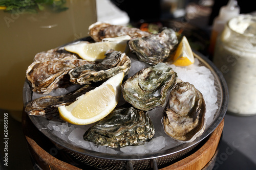 Close-up of sealed shells of fresh oysters lie on ice with lemon slices. The concept of a picnic. Luxury seafood