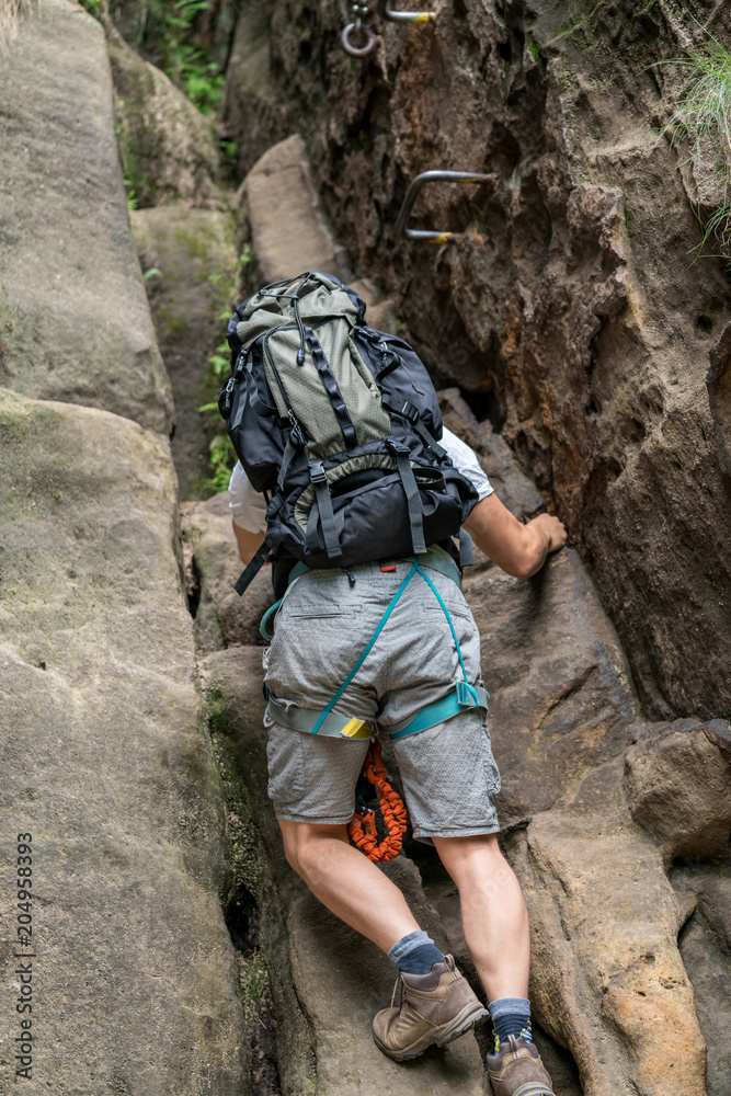 Mann mit Rucksack klettert an einem Berg in der sächsischen Schweiz Mann mit Rucksack klettert an einem Berg in der sächsischen Schweiz