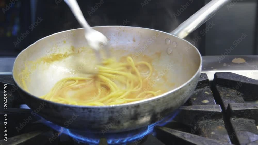 Person cooks pasta in pan, close up Person cooks pasta in pan, close up