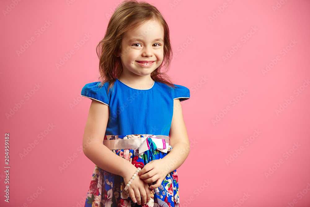 little girl wears beautiful blue dress on pink isolated background. little girl wears beautiful blue dress on pink isolated background.