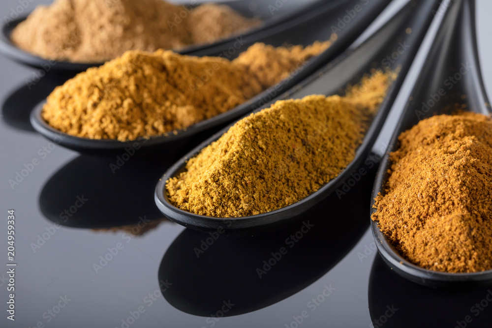 Small black bowls of Indian spices on black reflective background . Small black bowls of Indian spices on black reflective background .