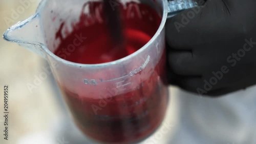 Close up, person holds measuring cup of red paint