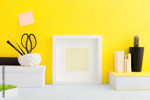 Creative desk with photo frame and yellow wall. photo