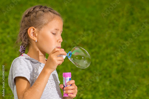 Portrait of funny lovely little girl blowing soap bubbles