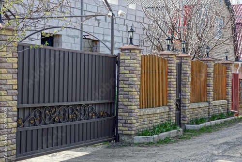 brown iron gates and a fence of bricks and boards on the street near the road