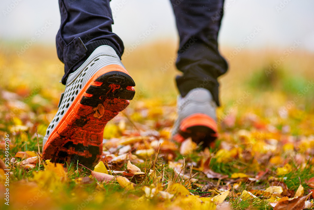 Closeup of sneakers on ground with autumn leaves and grass in park Closeup of sneakers on ground with autumn leaves and grass in park