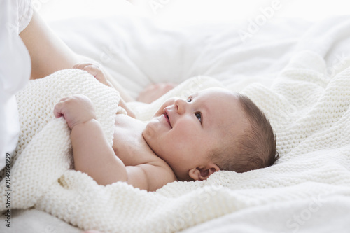 Newborn child relaxing in sunny bed after bath or shower. Happy and cheerful childhood.