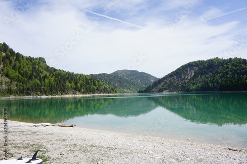 Very blue lake in the mountains of Bavaria in Germany with forrest