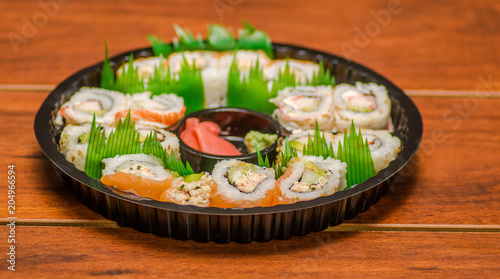 Large set of japanese sushi rolls on a black plastic plate
