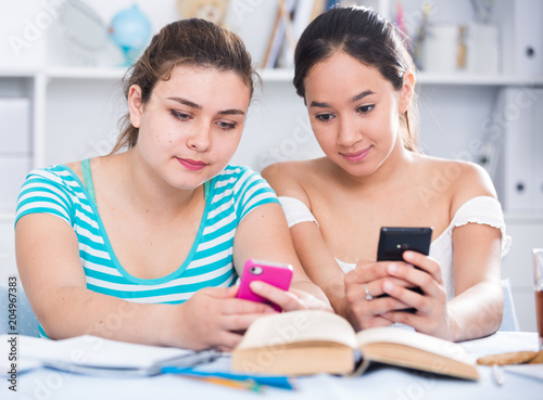 Smiling teenage girls using phones