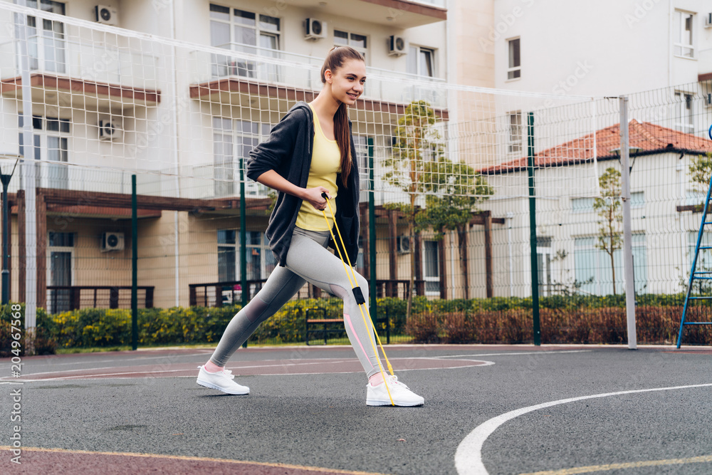 active young girl kneading leg muscles before exercising on an outdoor sports field active young girl kneading leg muscles before exercising on an outdoor sports field