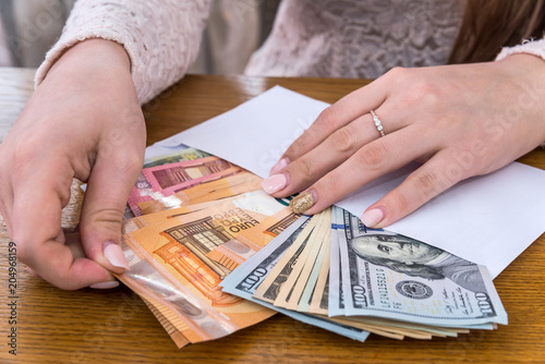 Envelope full of euro and dollar with female hands