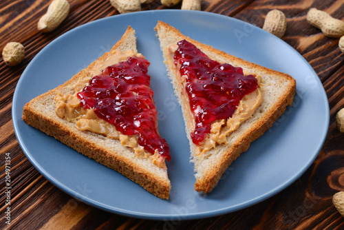 Peanut butter and jelly sandwich on wooden background. Space for text or design.