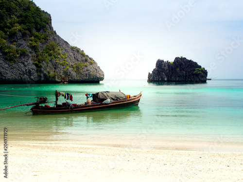 White sand beach and fisher man's boat in the blue sea.