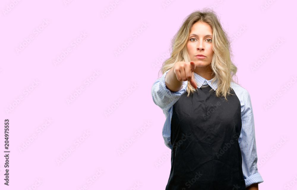 Young shop owner wearing black apron pointing to the front with finger Young shop owner wearing black apron pointing to the front with finger