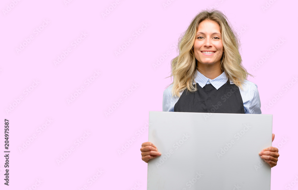 Young shop owner wearing black apron holding blank advertising banner, good poster for ad, offer or announcement, big paper billboard
