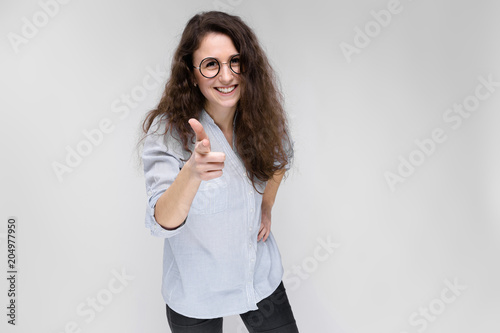 Young brunette girl with glasses. The girl points a finger forward. photo