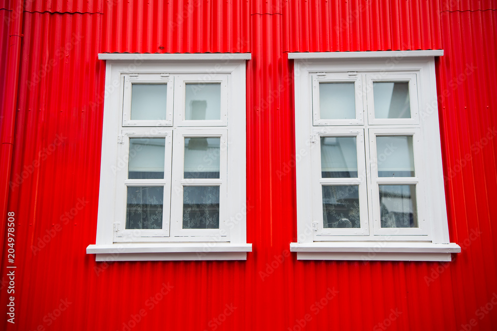 Windows in house in reykjavik, iceland. Building facade with red wall and white window frames. Architecture structure and design