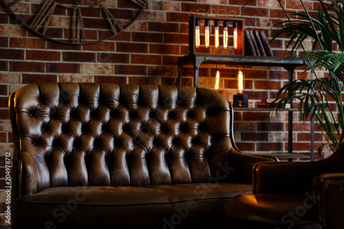 Loft interior. Leather couch and armchair in a dark room © Angelov