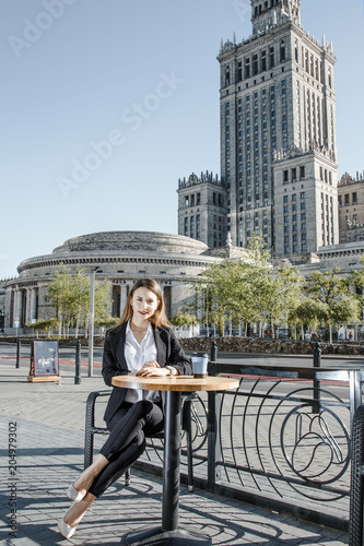 The girl is sitting at a coffee table in the business center of Warsaw. A business woman is waiting for a meeting in Warsaw near the Palace of Culture and Science.