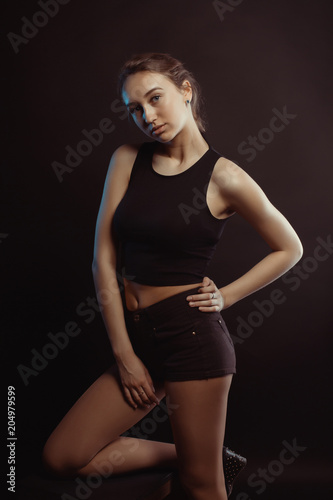 Studio photo session with a beautiful brunette model posing in the dark