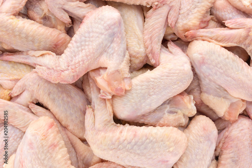 Raw chicken wings close-up. A bunch of chicken wings scattered over the surface.