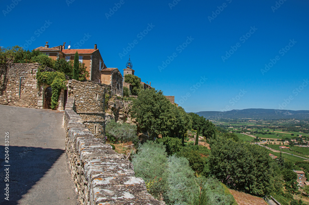 Panoramic view of street, house and hills of Provence under sunny blue sky, at the village of Menerbes. Located in the Vaucluse department, Provence-Alpes-Côte d'Azur region, southeastern France