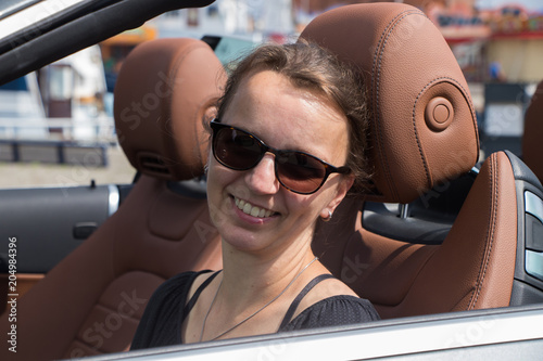   portrait of a beautiful smiling brunette woman driving in Luxury Convertible Sports Car © Riko Best