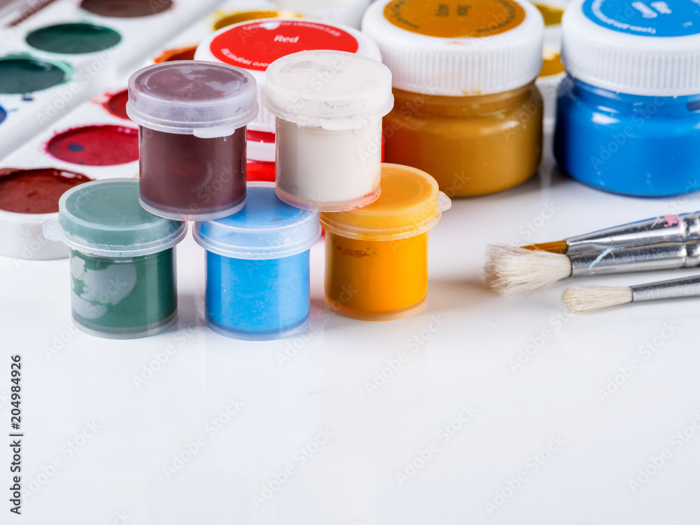 Acrylic paint in jars and tassels for drawing on a white background Acrylic paint in jars and tassels for drawing on a white background