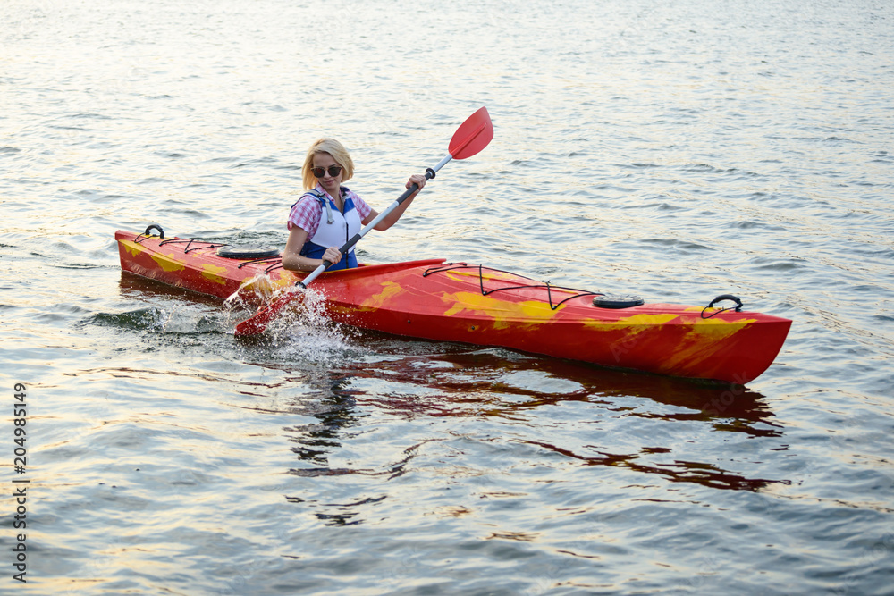 Young Woman Paddling Kayak on Beautiful River or Lake at the Evening