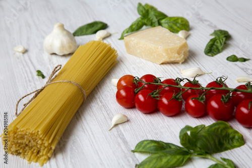 Ingredients for cooking italian pasta on a white wooden background, closeup.