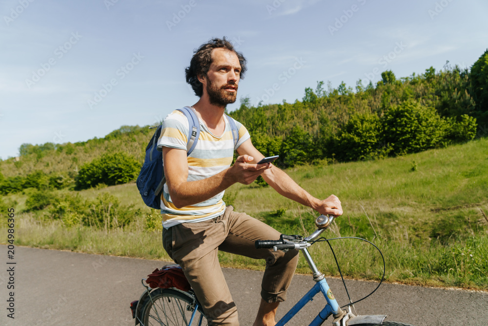Obraz premium young caucasian man biking through a field of rapeseeds