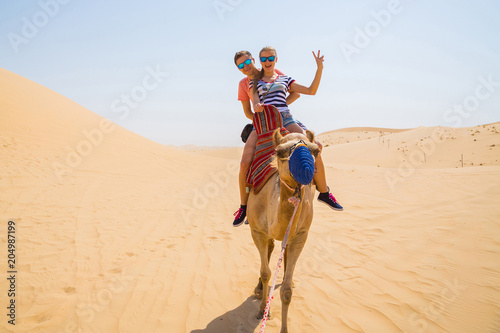 Young couple sitting on a camel in a desert photo