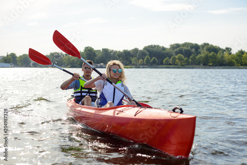 Young Happy Couple Paddling Kayak on Beautiful River or Lake