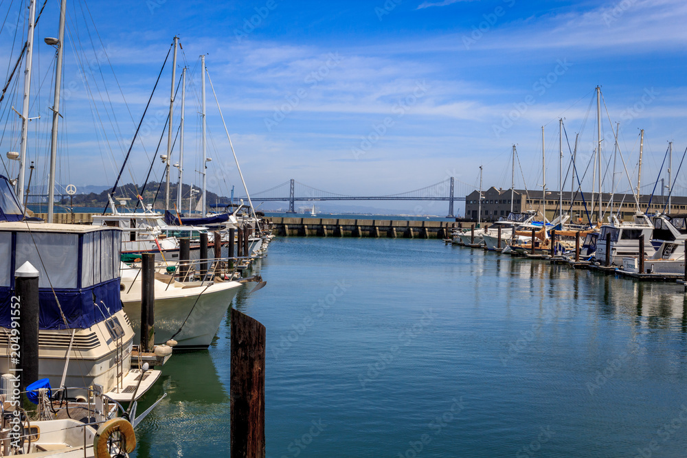 Boats lined up at a marina in San Francisco overlooking Bay Bridge