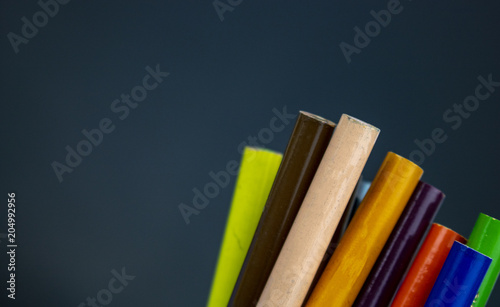 The ends of colored pencils stick out on a dark chalkboard background. Back to school colored pencils with lots of room for text! 
