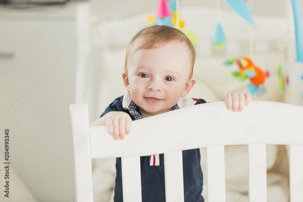 Toned portrait of smiling 1 year old baby boy in cot looking in camera Toned portrait of smiling 1 year old baby boy in cot looking in camera