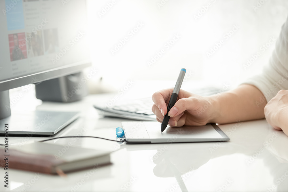 Fototapeta premium Closeup image of female graphic designer holding stylus and drawing on graphic tablet